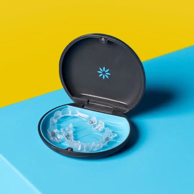 Allineatori Invisalign® nella loro custodia su sfondo giallo e blu