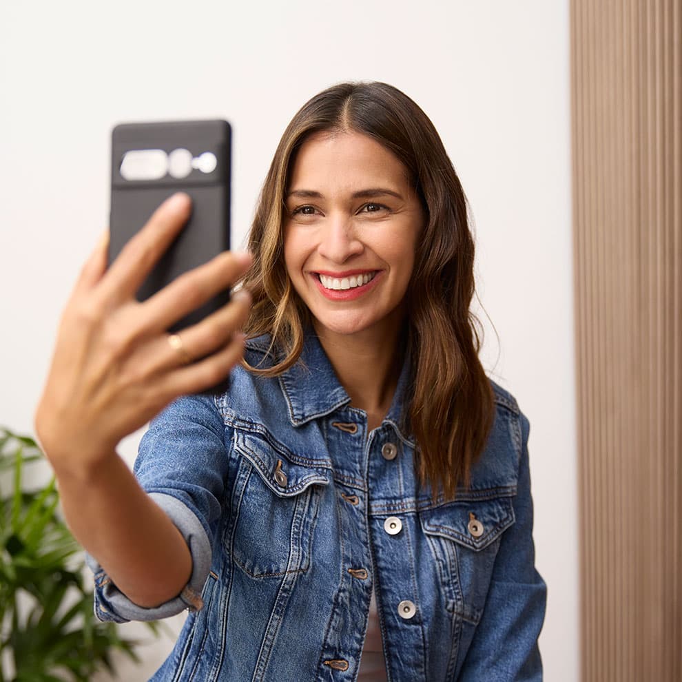 Una ragazza con una giacca di jeans sorride e si scatta una foto dopo il trattamento Invisalign®