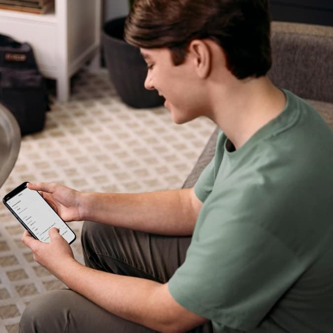 Il giovane sorride e fissa lo schermo del suo telefono